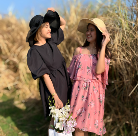 Sisters with straw hats around tall grass