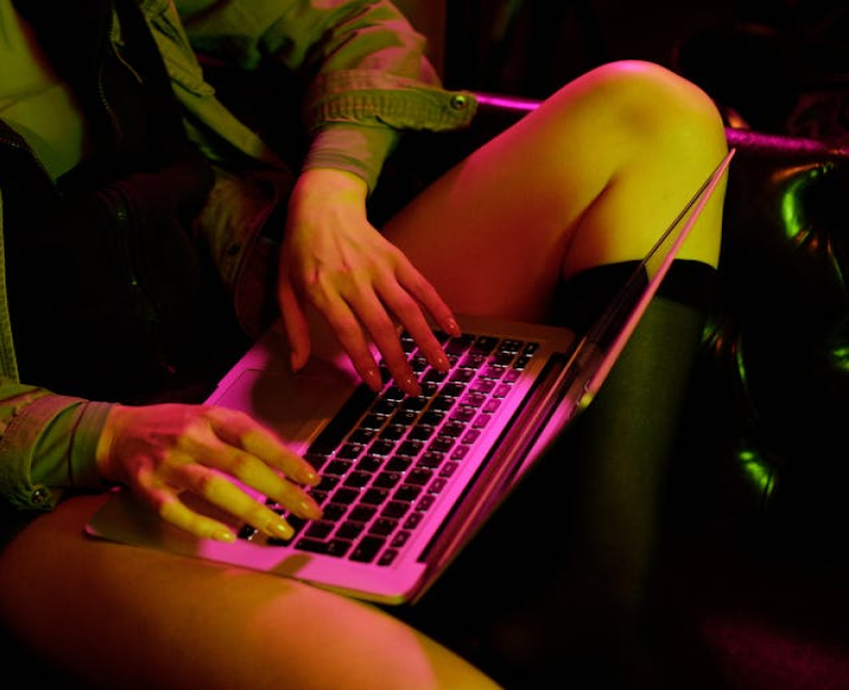 Sitting woman using laptop in neon lighting